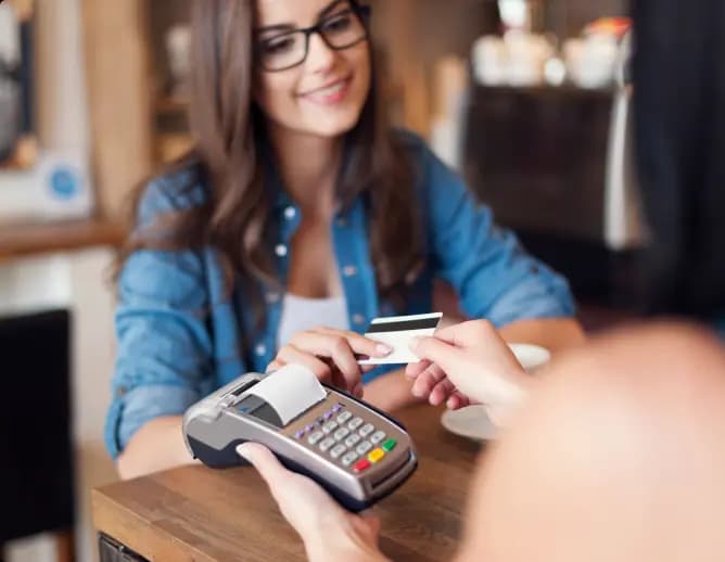 A woman using a credit card at a payment terminal, showcasing optimized payment processing in a retail environment.