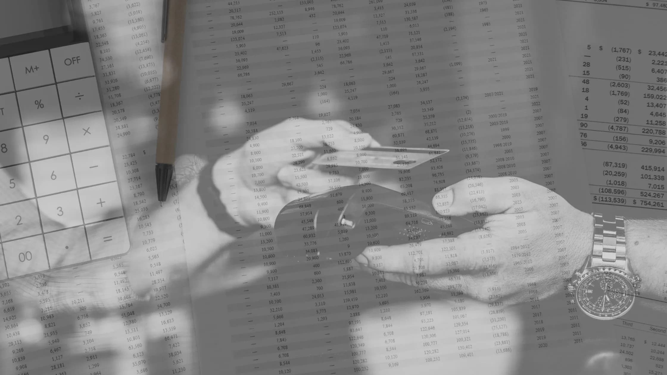 Hands holding a credit card with financial documents and a calculator in the background, representing the Visa and Mastercard settlement and its effects on merchants.