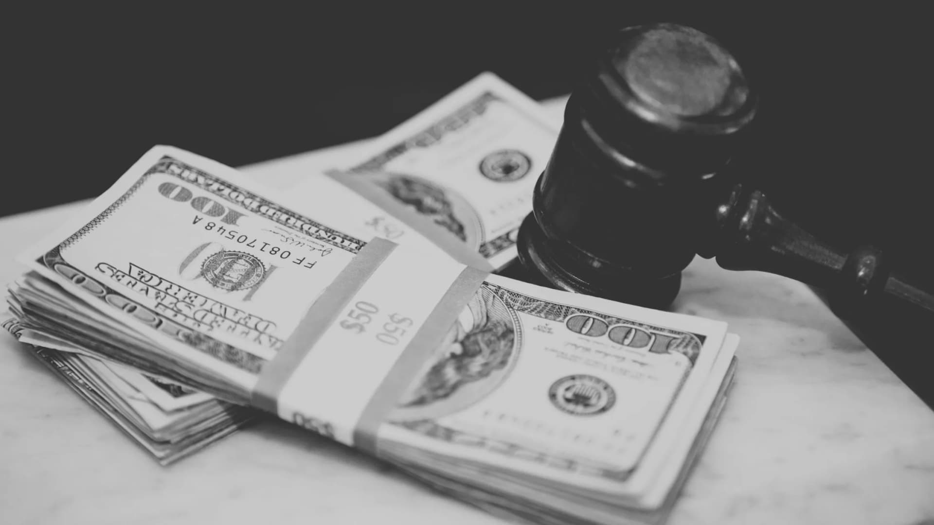Stack of hundred-dollar bills and a judge's gavel representing the financial and legal aspects of the Visa and Mastercard settlement.
